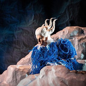 Ariel (Katharina Shakina) auf einem Felsen.