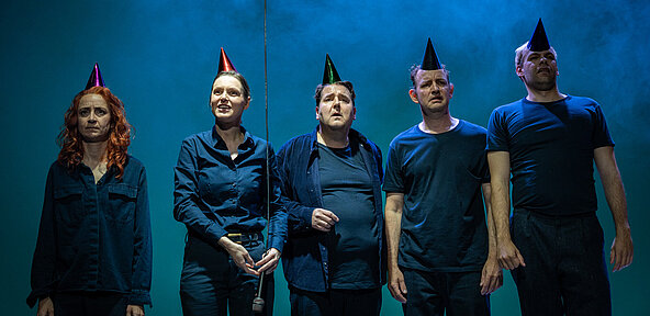 Fiffy (Franziska Werner), Zoe (Julia Friede), Tristan (Gerrit Frers), Dennis (Klaas Schramm) und Nico (Hagen Bähr) stehen frontal in einer Reihe. Sie haben bunte Partyhüte auf dem Kopf, hinter ihnen Bühnennebel.