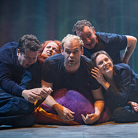 Tristan (Gerrit Frers), Fiffy (Franziska Werner), Nico (Hagen Bähr), Dennis (Klaas Schramm) und Zoe (Julia Friede) liegen auf einem lila Sitzsack bzw. aufeinander. Alle in ähnlicher blauer Kleidung.